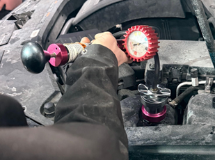 Technician pressure testing cooling system to diagnose overheating or coolant leaks
