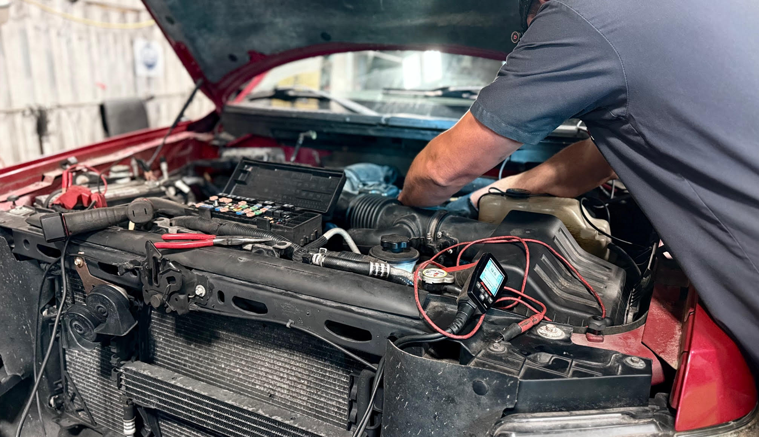 Technician performing automotive electrical diagnostics with multimeter and scan tool