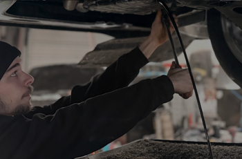 Dark dirty engine oil draining during oil change service