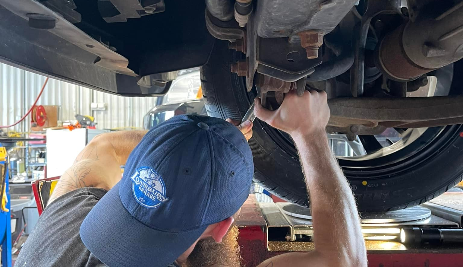 Technician inspecting suspension components including shocks, struts, control arms, and bushings